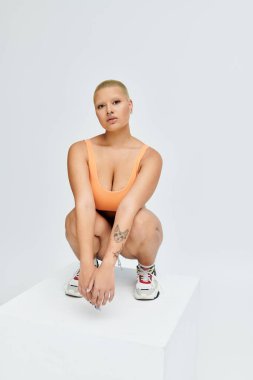 Genç kel bir kadın enerjisini canlı bir kıyafetle yayar, zarif bir şekilde kaideye konar..