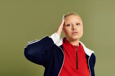 Genç kel bir kadın yeşil bir zemine karşı düşünceli ve canlı bir şekilde poz verir..