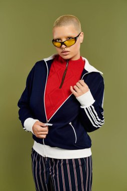 Genç ve kel bir kadın kendine has tarzını sergiliyor, kendine güvenen canlı kıyafetler içinde poz veriyor..