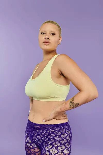 stock image A confident bald woman flaunts her vibrant outfit against a colorful backdrop.