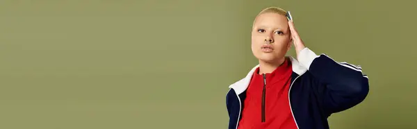 stock image A stylish young woman with a shaved head showcases her bold fashion choices and unique confidence.