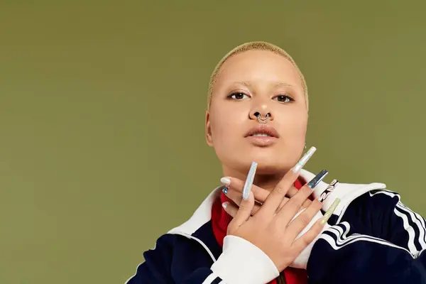 stock image A young bald woman showcases her vibrant style while confidently posing with elaborate nails.