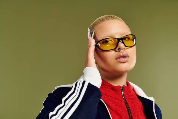 Молодая лысая женщина демонстрирует свой яркий стиль, делая уверенную позу в помещении.