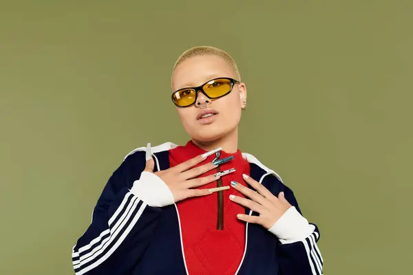 stock image The young bald woman confidently models vibrant clothing with unique accessories and sunglasses.