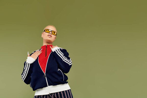 The confident bald woman showcases vibrant clothing while striking a dynamic pose with flair.