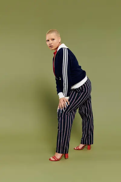 stock image A striking young bald woman showcases her vibrant outfit while striking a confident pose.