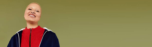 Живая молодая женщина уверенно улыбается, демонстрируя свой уникальный стиль и радостный дух.