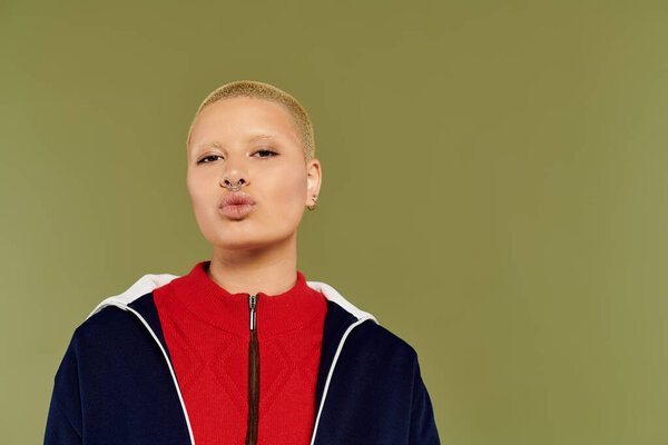 A bold young woman in colorful attire strikes a playful pose, exuding confidence and warmth.