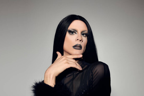 A fashionable gender fluid person showcases a striking black outfit, exuding elegance and confidence.