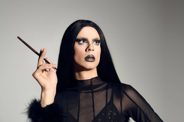 A gender fluid person captivates with bold makeup and a chic black ensemble while posing confidently.