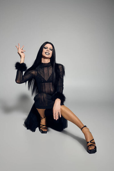 A striking drag queen showcases their unique style in a fashionable black outfit, exuding confidence and flair.