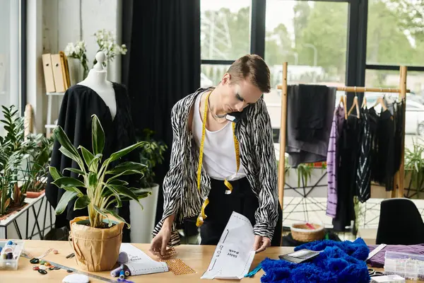 Renkli malzemeler ve ilham verici tasarımlarla çevrili bir moda tasarımcısı..