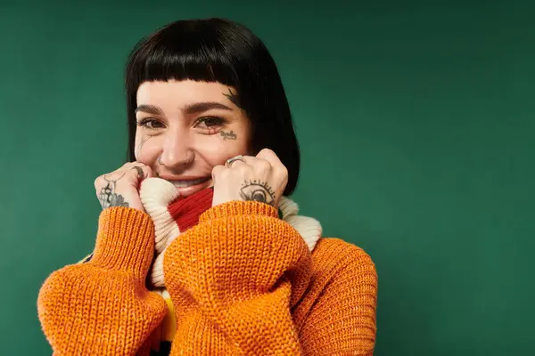 stock image A cheerful young woman with short hair smiles while wearing a warm, colorful sweater and posing comfortably.