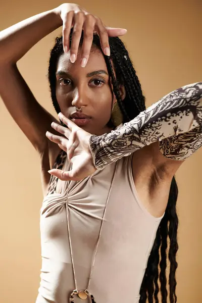 stock image A confident young woman showcases her stylish attire while posing creatively in a warm setting.