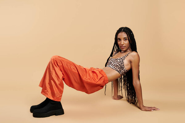 Молодая женщина показывает свой стильный взгляд на теплом, нейтральном фоне.