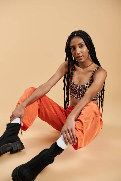 Уверенная в себе молодая женщина демонстрирует свой уникальный стиль шикарным нарядом в теплой тонированной обстановке.