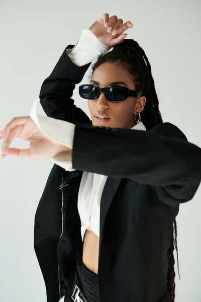 Модная молодая женщина уверенно позирует, привлекая внимание своим неповторимым стилем и изяществом.