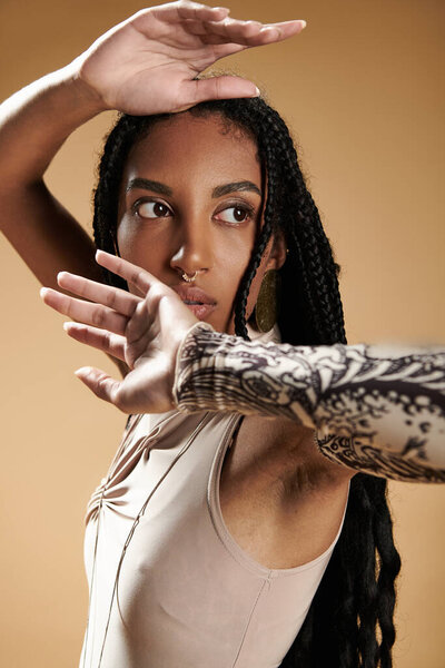 Молодая женщина изящно позирует, подчеркивая свой модный наряд и замысловатые татуировки.