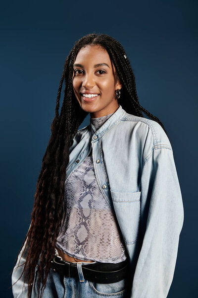A fashionable young woman with braids exudes confidence while posing against a vibrant background.
