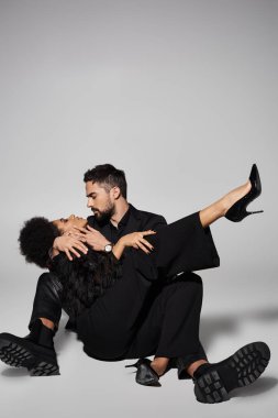 Bir çift samimi bir kucaklaşmayı paylaşıyor, ileri moda kıyafetlerle romantizm ve zarafet yayıyor..