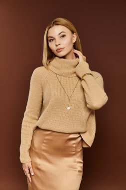 Genç ve güzel bir kadın, sonbahar kıyafetlerini sıcak renklerin ortasında özgüvenle sergiliyor..