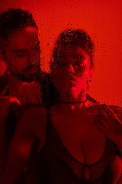 A couple shares an intimate moment, surrounded by a warm red glow and misty textures.