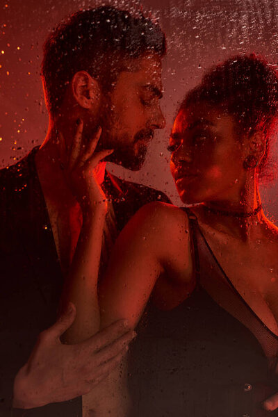 Любящая пара разделяет электрический момент, освещенный мягким освещением и окруженный каплями.