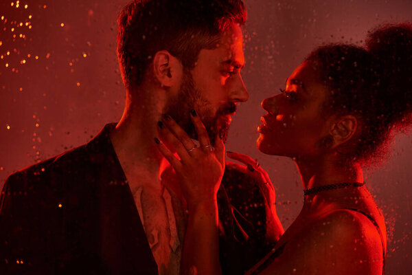 Пара выражает глубокую привязанность и желание, окруженные очаровательной красной подсветкой.