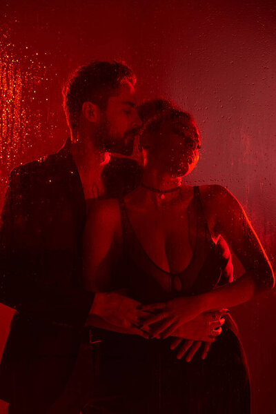Пара стоит рядом, их любящие лица освещены красным светом и капельками.