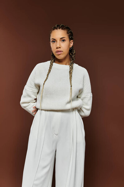 Dressed in autumn attire, a beautiful young woman exudes confidence against a warm backdrop.