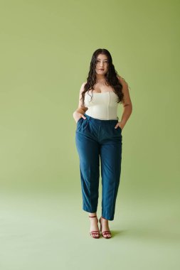 Şık bir korse ve pantolon giyen kendinden emin genç bir kadın doğal güzellik ve güç yayar..