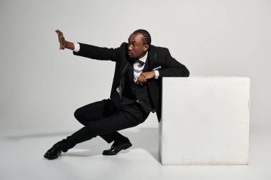 Takım elbiseli genç bir adam şık bir poz veriyor. Tarafsız bir ortamda özgüven ve zarafet sergiliyor..