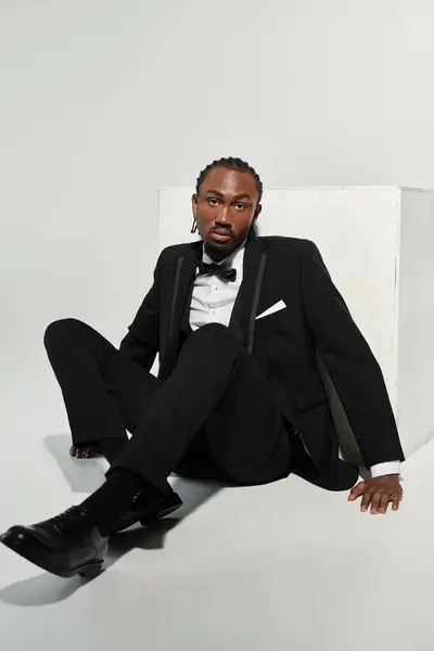 stock image A sharply dressed young man in a suit exudes confidence while striking a stylish pose on a plain backdrop.