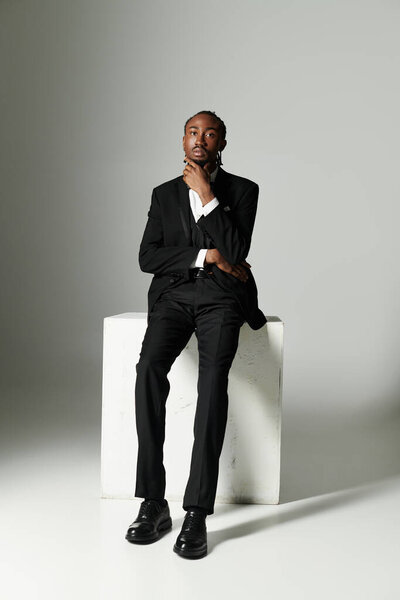 A confident young man in a fitted suit poses with determination against a monochrome backdrop.