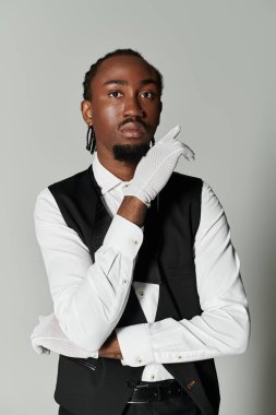 A young African American man, dressed in a formal suit and vest, poses thoughtfully, showcasing elegance. clipart