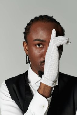 Genç bir Afro-Amerikalı, gri aksesuarlar ve parlak bir takım elbise içinde moda anlayışını sergiliyor..