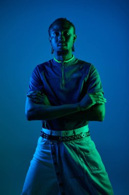 A young African American man showcases his style while posing confidently under neon lights. clipart