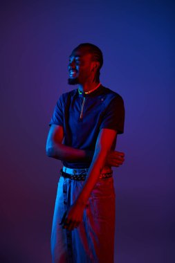 Genç bir Afrikalı Amerikalı, renkli neon ışıklarla aydınlatılmış şık bir şekilde poz veriyor..