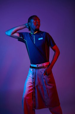 Moda bir genç adam canlı neon ışıkta poz veriyor, modern stil ve özgüven sergiliyor..