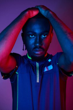 Moda giysileri içinde genç bir Afrikalı Amerikalı kendini çarpıcı neon ışıklarının altında, ışık saçarak ifade ediyor..