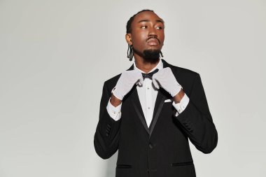 Sivri takım elbiseli ve yelekli genç bir Afrikalı Amerikalı zarif poz verirken kendine güvenir..