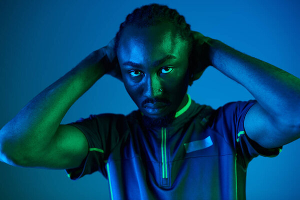 Молодой человек демонстрирует свой стиль одежды на завораживающем неоновом фоне, создавая энергичную атмосферу.