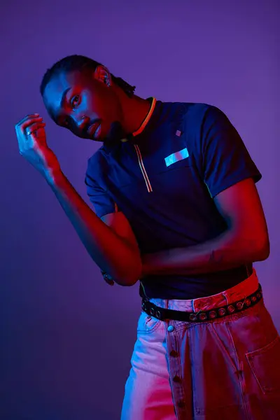 stock image A young African American man poses confidently in a studio, surrounded by captivating neon lights.