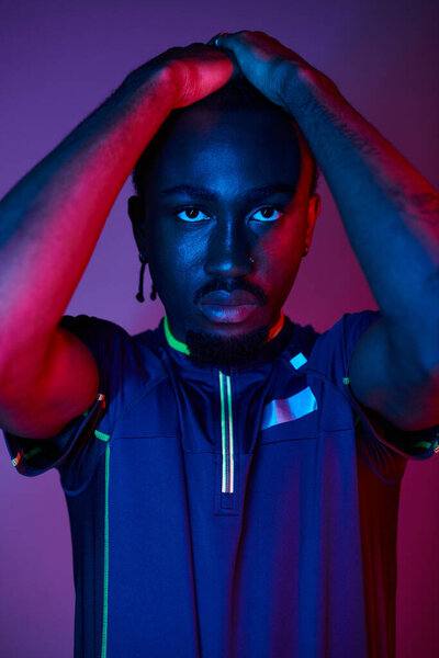 Молодой афроамериканец в модном наряде выражает себя под яркими неоновыми огнями, излучающими стиль.
