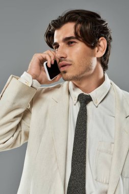 Şık giyinmiş genç bir adam, kendine güvenen tavırlarını sergileyerek bir telefon görüşmesi yapar..
