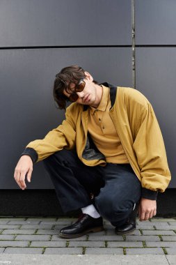 Genç bir adam, kendine güvenen bir şekilde poz verirken bir sonbahar kıyafetinde moda anlayışını sergiliyor..