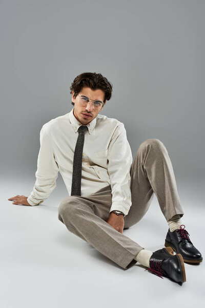 Молодой человек, одетый в элегантный наряд, очаровывает своей уверенной позой, излучающей шарм и изысканность..