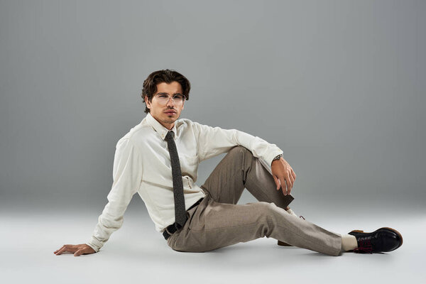 Красивый молодой человек демонстрирует свой стильный формальный наряд, изящно позируя в студии.