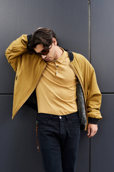 Молодой красивый мужчина уверенно демонстрирует свой модный осенний наряд, позируя непринужденно на современном фоне.