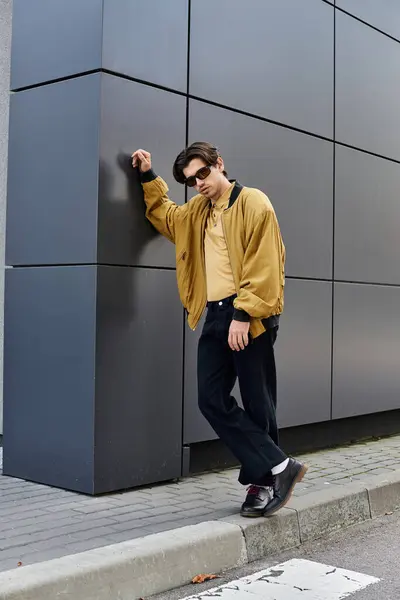 stock image A stylish young man stands confidently, wearing a trendy autumn outfit, against a sleek urban backdrop.